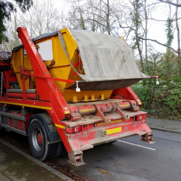 Yellow skip being collected by a skip collection vehicle from a street in Cardiff